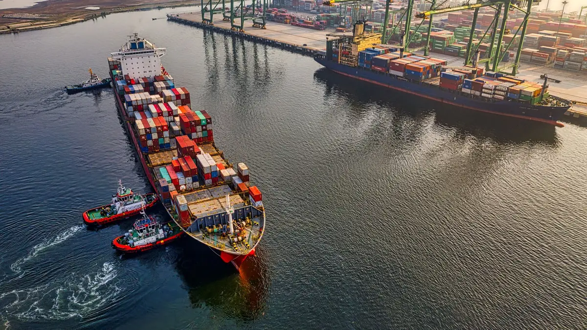Container e gru in un porto commerciale italiano durante le operazioni di carico