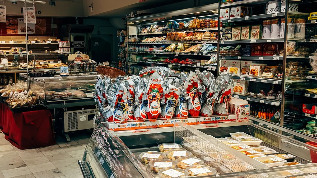 Cliente che confronta prezzi e prodotti alimentari negli scaffali di un supermercato